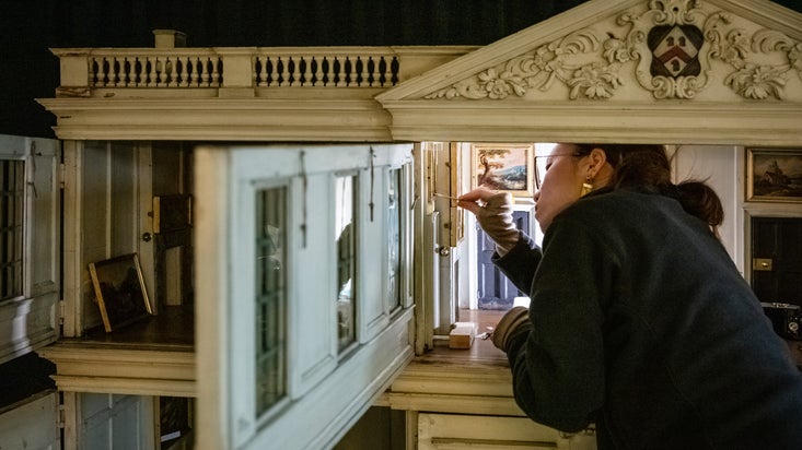 A conservator working on a doll's house